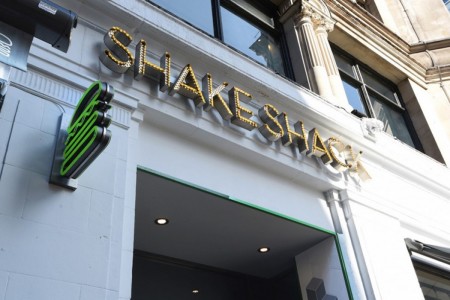 Shake Shack, Leicester Square - white exterior of building with gold branding and neon burger sign