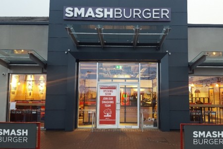 Smashburger, Dunfermline - exterior with branding, glass awning, grey front with white branding. Opening soon sign on window.