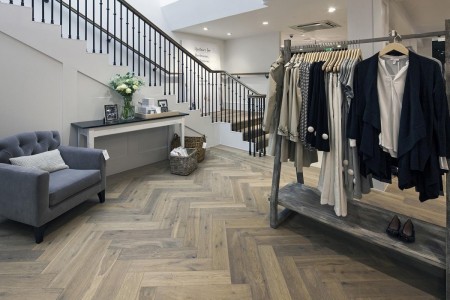 The White Company, Norwich - clothes hanging on a rail with a wooden frame, wooden flooring, staircase and seating area at the bottom of stairs