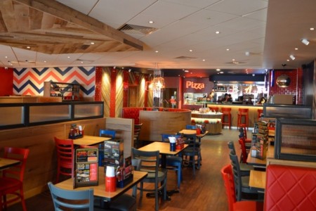 Pizza Hut, Bristol - bright interior with wooden accents around booths and on ceiling, red and blue wooden chairs
