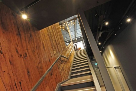 Shake Shack, New Oxford Street, London - wooden cladding on walls, looking up metal staircase