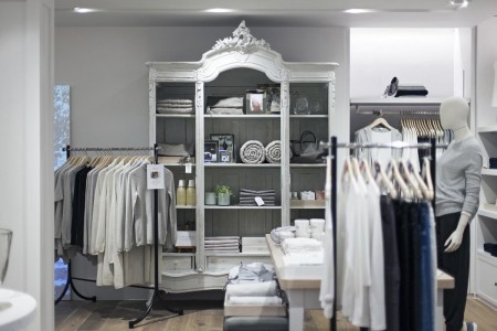 The White Company, Norwich - fancy white cabinet with blankets, towels, plants in, clothing rails around it