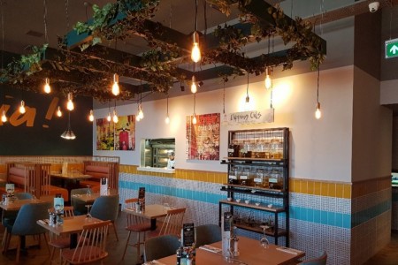 Prezzo, Weston Super Mare - ceiling decoration with artificial vines, exposed lightbulbs, bright blue and yellow tiling, wooden tables and chairs