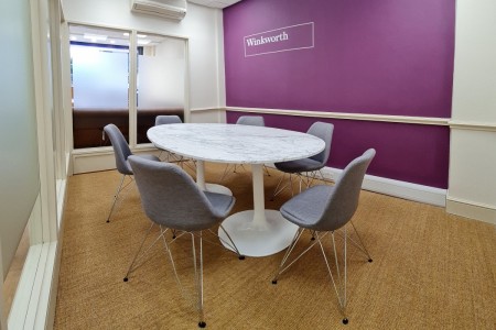 Winkworth Estate Agents, Crystal Palace - small marble table with grey chairs and purple wall with logo