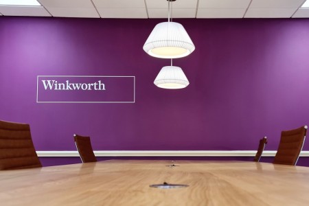 Winkworth Estate Agents, Crystal Palace - wooden desk and brown office chairs, purple wall with logo 