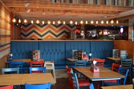 Pizza Hut, Bristol - hanging exposed lightbulbs, striped coloured walls in blue, red and white and blue sofa seating with tables and chairs aorund