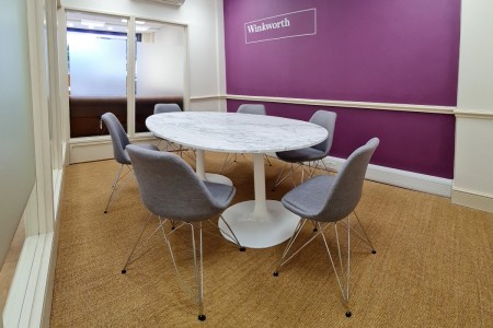 Winkworth Estate Agents, Crystal Palace - meeting room with carpet, purple wall with logo, grey seats around a marble table 