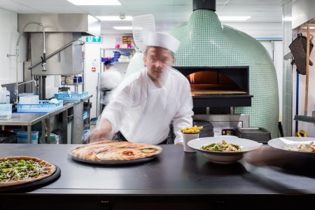 Wildwood, Crawley - kitchen area with a large pizza oven in centre and chefs serving pizzas