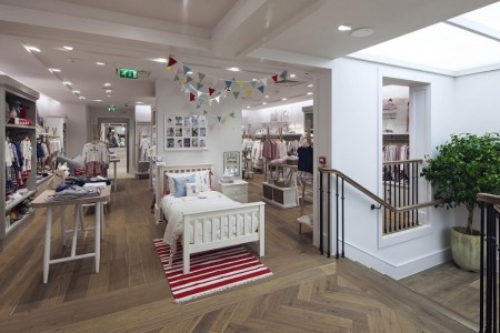 The White Company, Norwich - white children's bed, wooden parquet flooring, white walls, bunting hanging from the ceiling