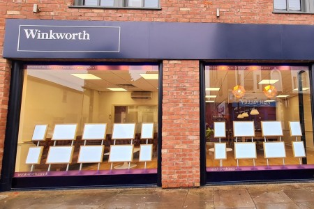 Winkworth Estate Agents, Crystal Palace - exterior of building showing purple branding and large windows with displays set up