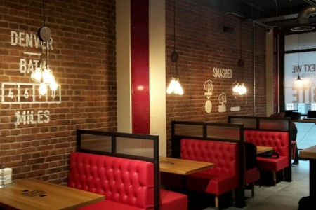 Smashburger, Bath - expose brickwork, red leather booth seating and wooden tables