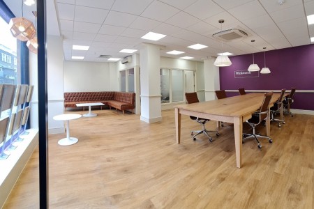 Winkworth Estate Agents, Crystal Palace - large open office with table, leather chairs, leather sofa and purple wall with logo