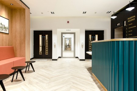 Prudential Buildings, Bristol - light wooden floor, seating area to the left with small tables, teale reception desk to the right, doors in front