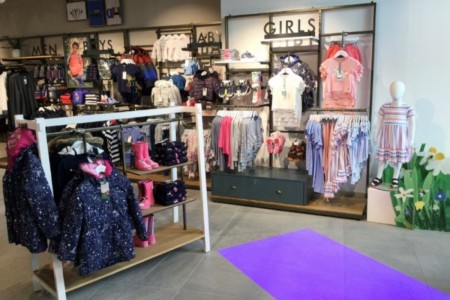 Joules, Longford, Ireland - girls' clothing section with wooden clothing displays, bright purple floor graphics on grey tiles