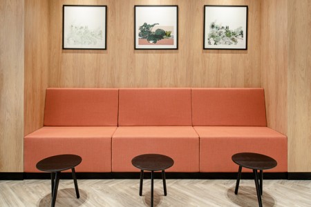 Prudential Buildings, Bristol - reception seating area with sofa in salmon pink, dark wooden tables and light wood panelling
