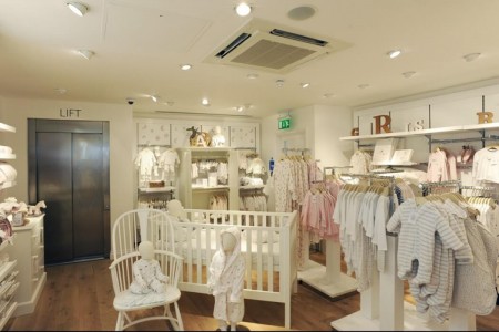 The White Company, Stamford - children's clothes area with white cot, white chair, white walls, wooden flooring