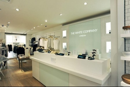 The White Company, Stamford - POS area with tills on a white desk with a glass wall and light up logo behind