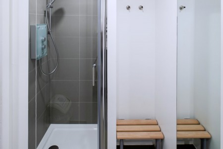 Prudential Buildings, Bristol - shower stalls with grey tiling and white walls, wooden benches 