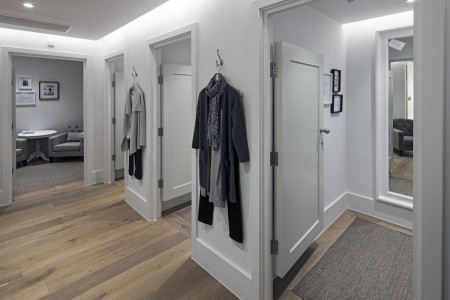 The White Company, Norwich - white painted fitting rooms with hardwood floor, clothes hanging up outside the rooms