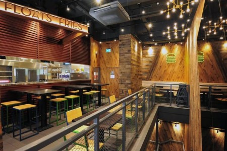 Shake Shack, New Oxford Street, London - wooden clad walls with exposed brick work, neon burger signs, kitchen area, stools and tables