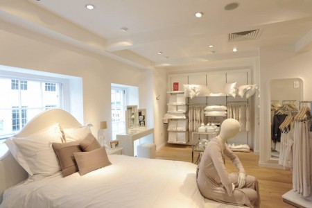 The White Company, Stamford - white bed linen, mannequin with white clothes, white walls, white pillows, light wooden floor