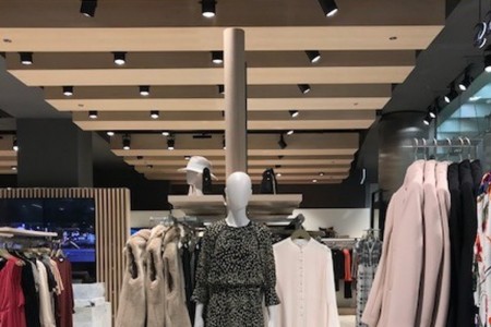 Reiss, Canary Wharf - wooden details in ceiling with lighting, clothing displays below