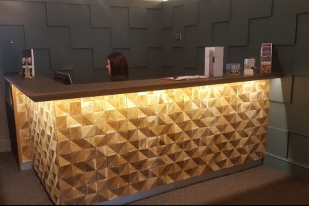 The Chequers Hotel, Newbury - check in desk which is a wooden decorative pattern and backlit