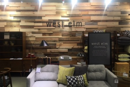 West Elm - grey sofa, West Elm logo on wall behind which is made out of wood