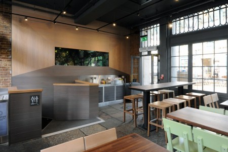 Shake Shack, Covent Garden - wooden seating areas with stone tiled floor, grey divider leading to downstairs and toilets