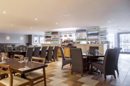 Prezzo, Abergavenny - brown leather chairs, dark wood tables, wooden flooring, bar area with bottles behind